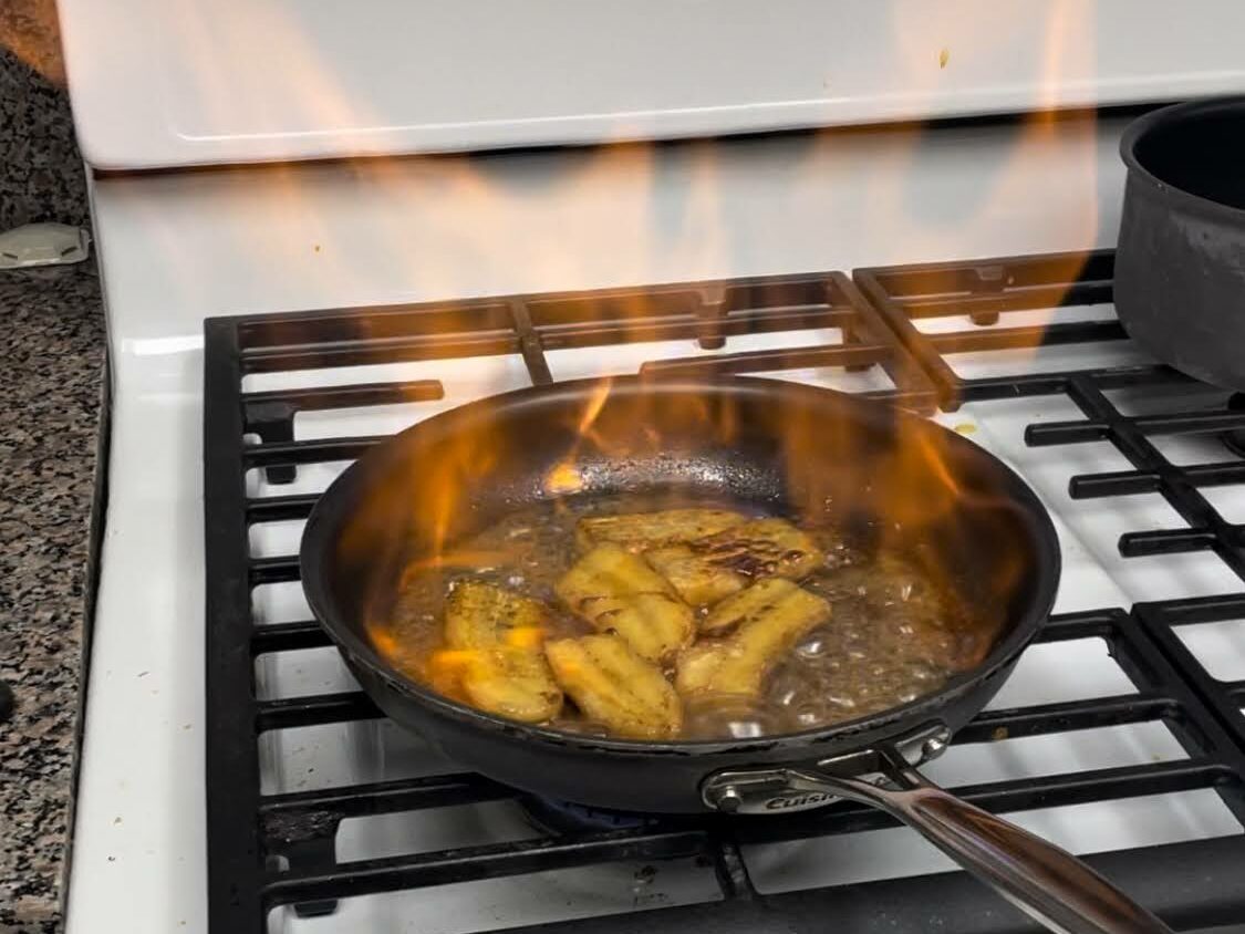 Alt Text: An image of bananas in a fry pan with flames coming out of it.